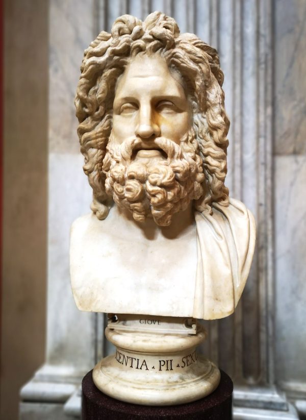 Estatua romana de mármol del dios Júpiter, de pie, con el torso desnudo y un manto sobre las piernas.